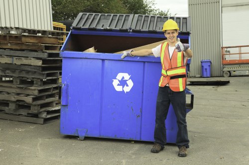 Supervisor completing a risk assessment form beside a skip